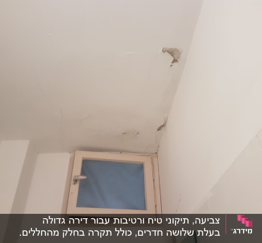 קיר עם סדקים ותקרה מתקלפת ליד חלון קטן